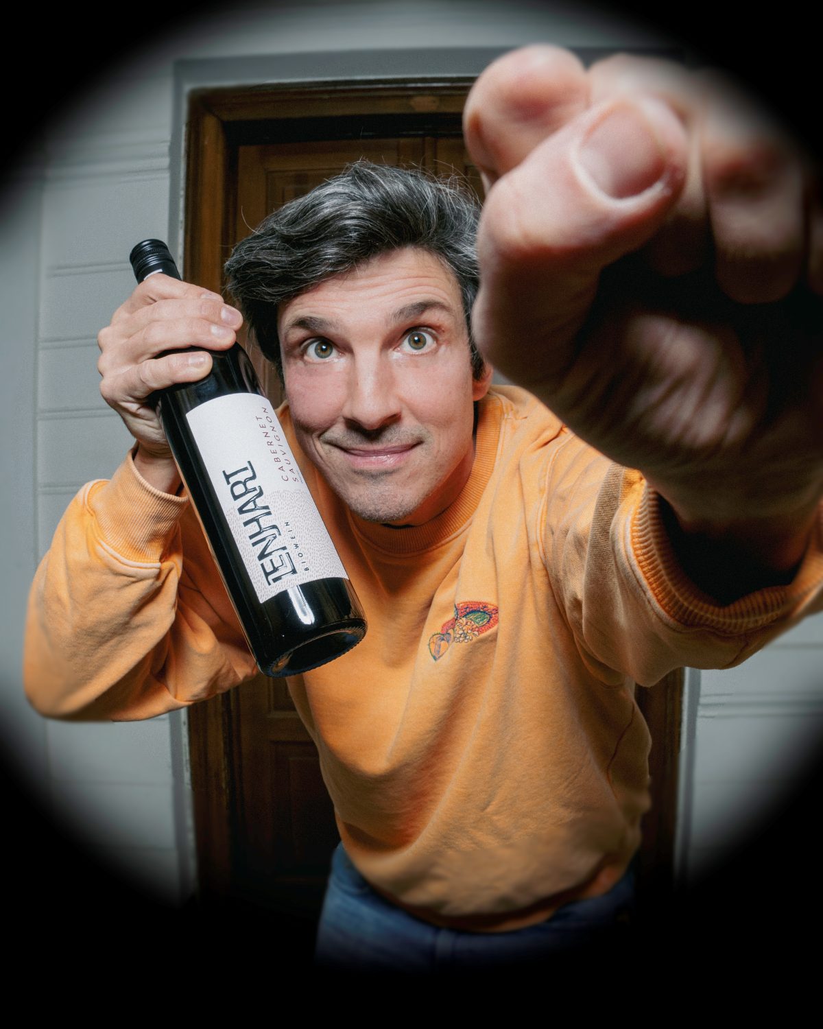 David mit einer Flasche Cabernet Sauvignon, durch den Türspion gesehen